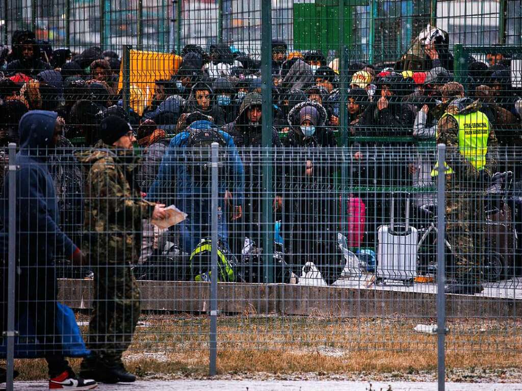 Menschen warten am Grenzbergang hinter einem Tor auf die Einreise nach Polen.