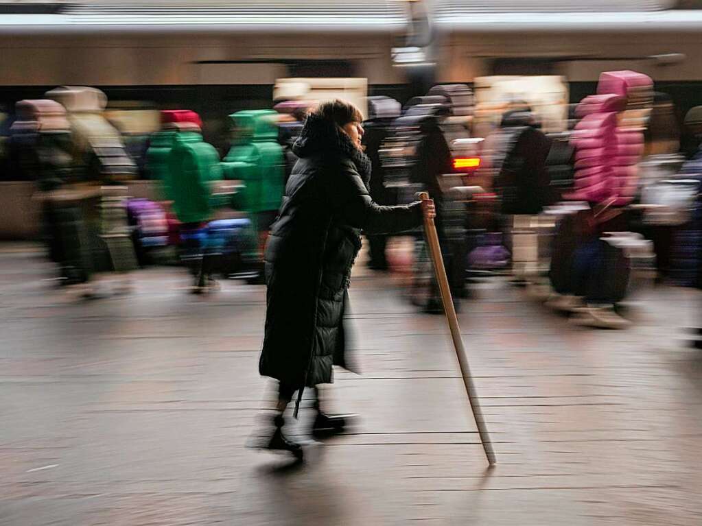 Kiew: Eine Frau geht mit einem Gehstock den Bahnsteig entlang, whrend Menschen in einen Zug nach Lwiw einsteigen.