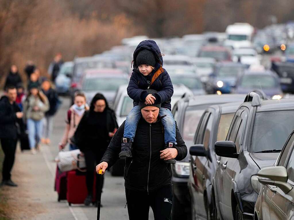 Ukraine: Flchtlinge gehen mit ihrem Gepck an Fahrzeugen entlang, die am Grenzbergang stehen.