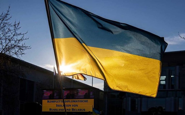 Die Fahne der Ukraine leuchtet bei einer Demonstration.  | Foto: Paul Zinken (dpa)