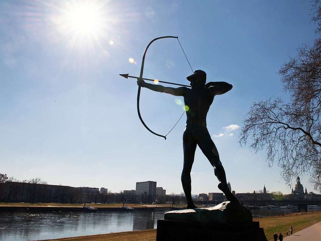 Dresden: Passanten gehen am Ufer der Elbe vor der Kulisse der Frauenkirche hinter der Plastik Bogenschtze von Ernst Moritz Geyger entlang.