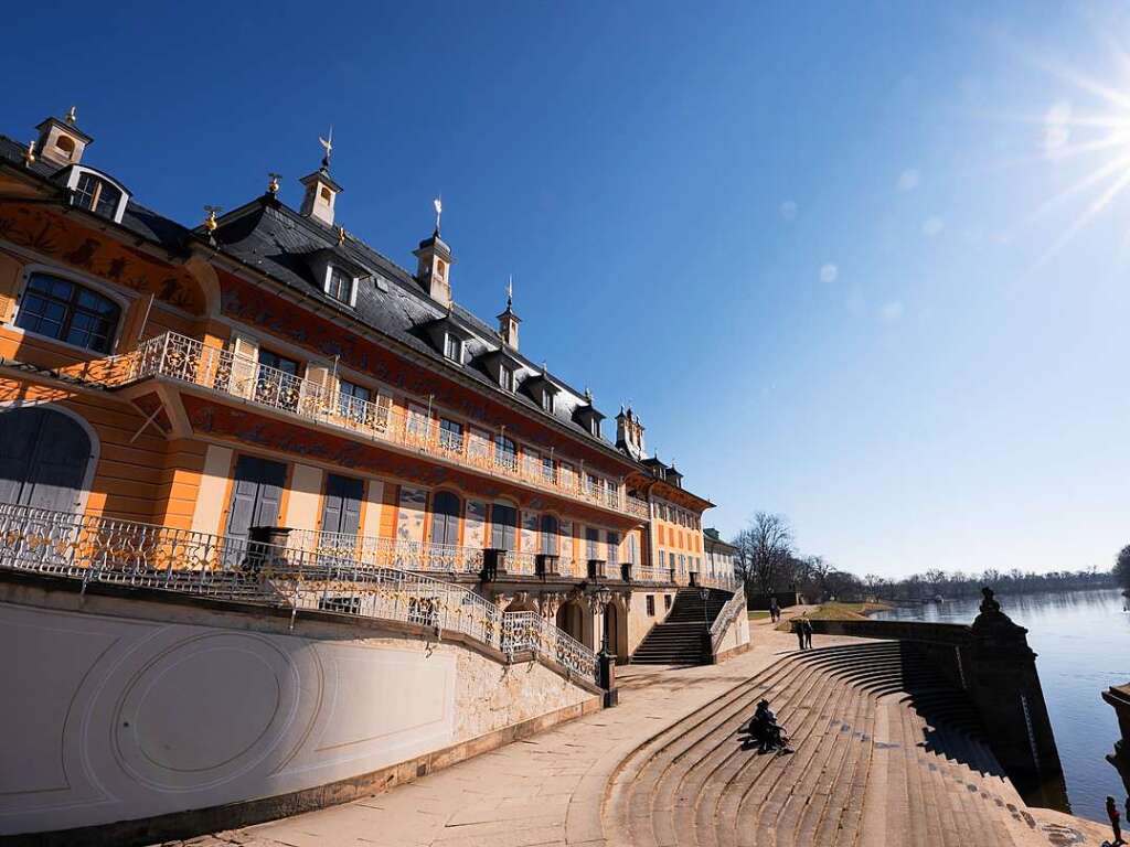 Dresden: Passanten sitzen im Schloss und Park Pillnitz vor dem Wasserpalais auf einer Freitreppe am Ufer der Elbe.