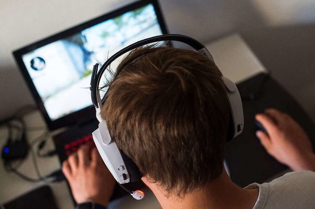 Ein Jugendlicher sitzt mit einem Headset vor einem Laptop.  | Foto: Lino Mirgeler (dpa)