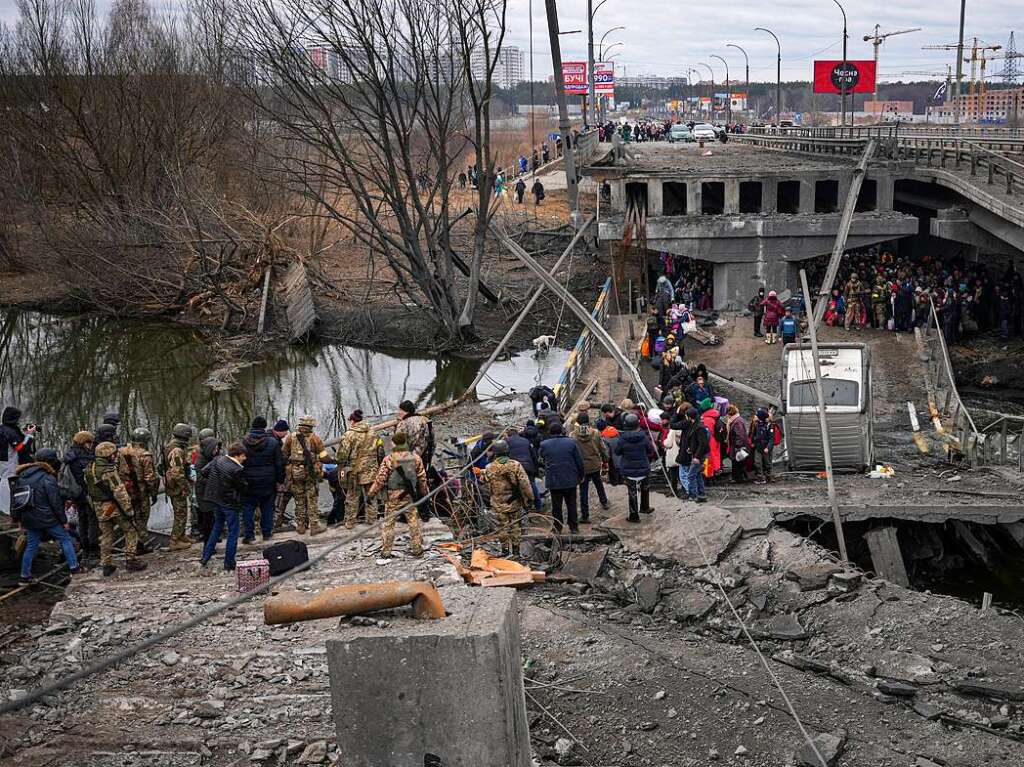 Menschen berqueren den Fluss Irpin auf einem improvisierten Weg unter einer zerstrten Brcke, whrend sie aus der Stadt Irpin fliehen.