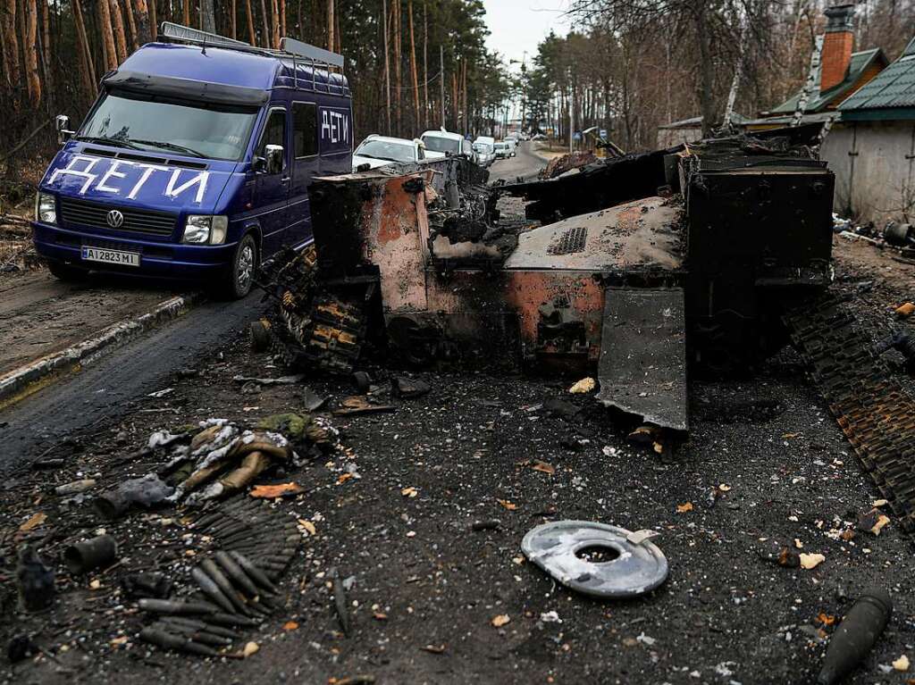 Ein Lieferwagen mit der Aufschrift "Kinder" fhrt an einem zerstrten russischen Panzer vorbei.