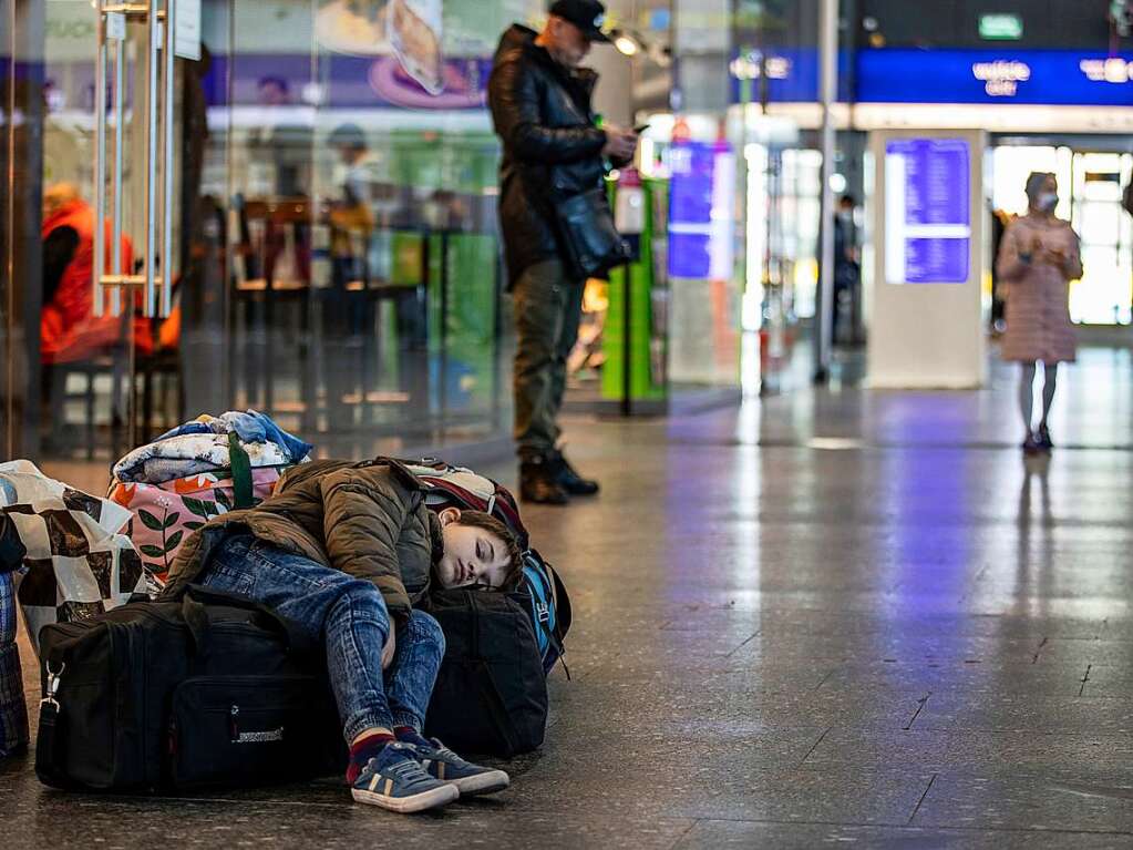 Polen, Warschau: Ein kleiner Junge liegt schlafend auf ein paar Reisetaschen, seine Mutter sucht nach Mglichkeiten der Weiterreise. Am Hauptbahnhof in Warschau treffen weiterhin jeden Tag tausende Flchtende aus der Ukraine ein.