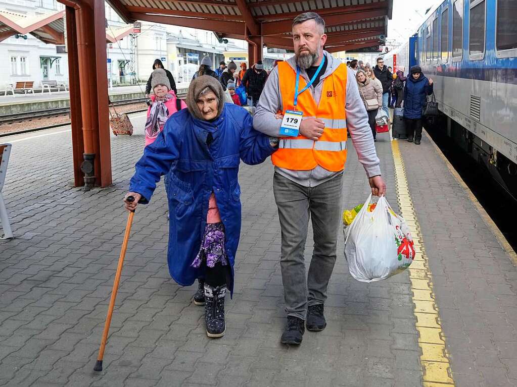 Polen, Przemysl: Ein Freiwilliger hilft auf dem Bahnsteig eines Bahnhofs einer lteren Frau, die aus der Ukraine geflchtet ist.