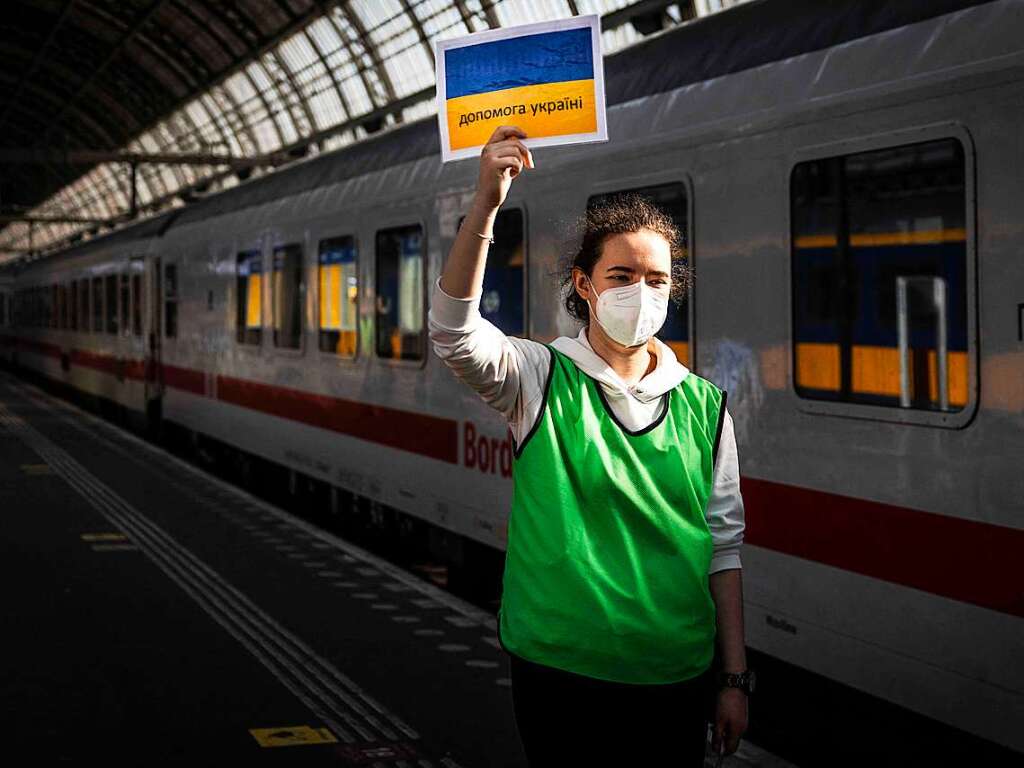 Niederlande, Amsterdam: Eine Mitarbeiterin hlt ein Schild hoch, um die Menschen aus der Ukraine in Empfang zu nehmen, die von Berlin nach Amsterdam weitergereist sind.