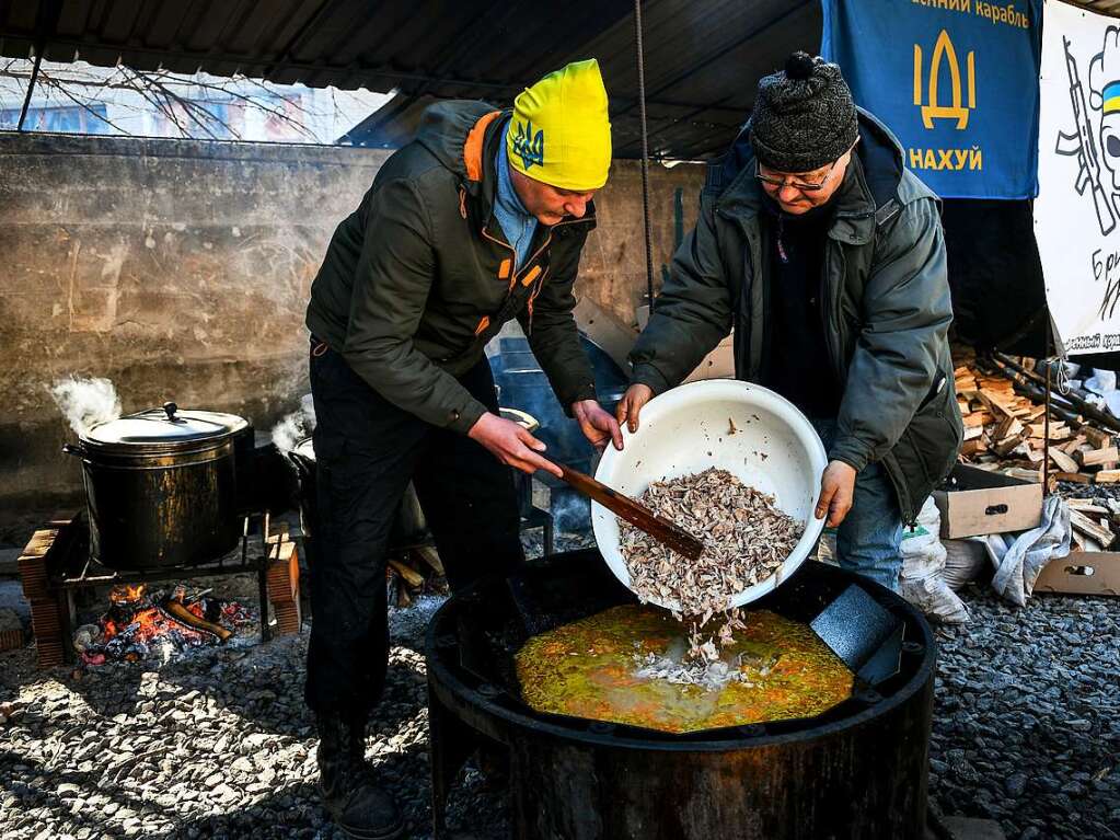 Saporischschja: Zwei Mnner bereiten Essen vor auf dem Gelnde eines lokalen Verteidigungszentrums.