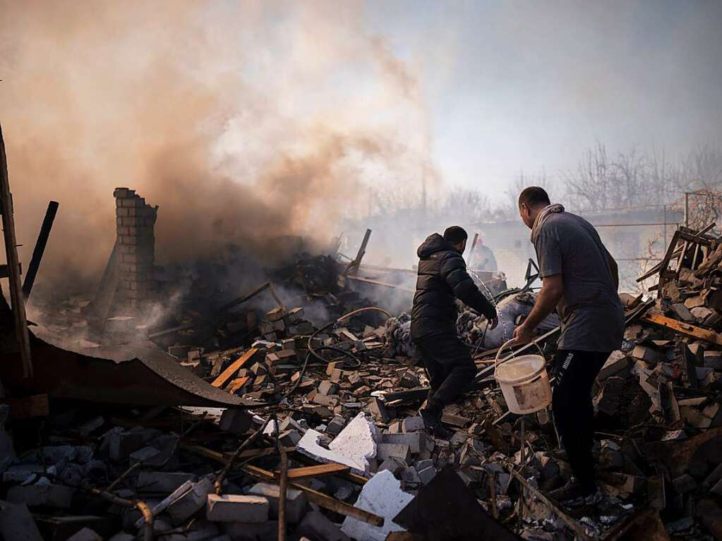 Charkiw: Nachbarn versuchen das Feuer eines Hauses zu lschen, das nach einem russischen Angriff in Charkiw zerstrt wurde.