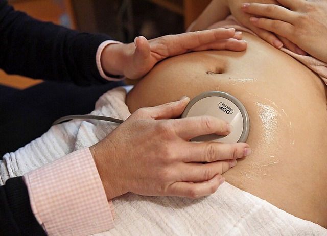 Eine Hebamme kontrolliert die Herztne eines Babys.  | Foto: Uli Deck (dpa)