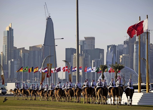 Reiter auf ihren Kamelen sind auf dem ...e Skyline von West Bay Doha zu sehen.   | Foto: Christian Charisius (dpa)