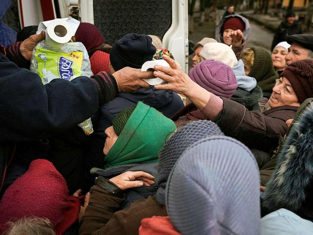 Ein Mann verteilt Toilettenpapierrollen an die Menschen in Butscha.