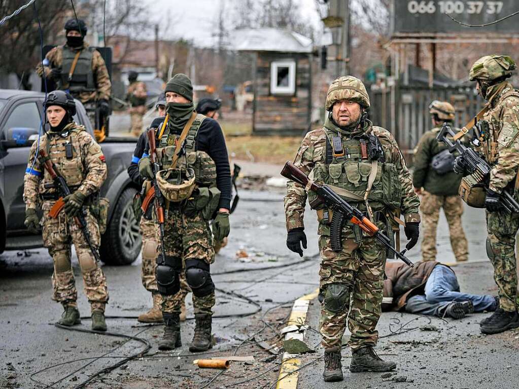 Ukrainische Soldaten stehen im ehemals russisch besetzten Kiewer Vorort Butscha und untersuchen die Leichen von Zivilisten auf Sprengfallen.