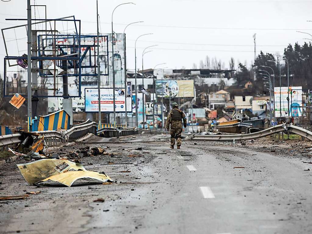 Ein ukrainischer Soldat geht  auf einer zerstrten Strae.