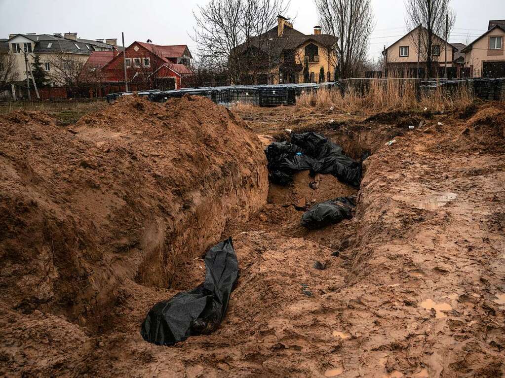 Schwarze Leichenscke liegen in einem Massengrab in Butscha.