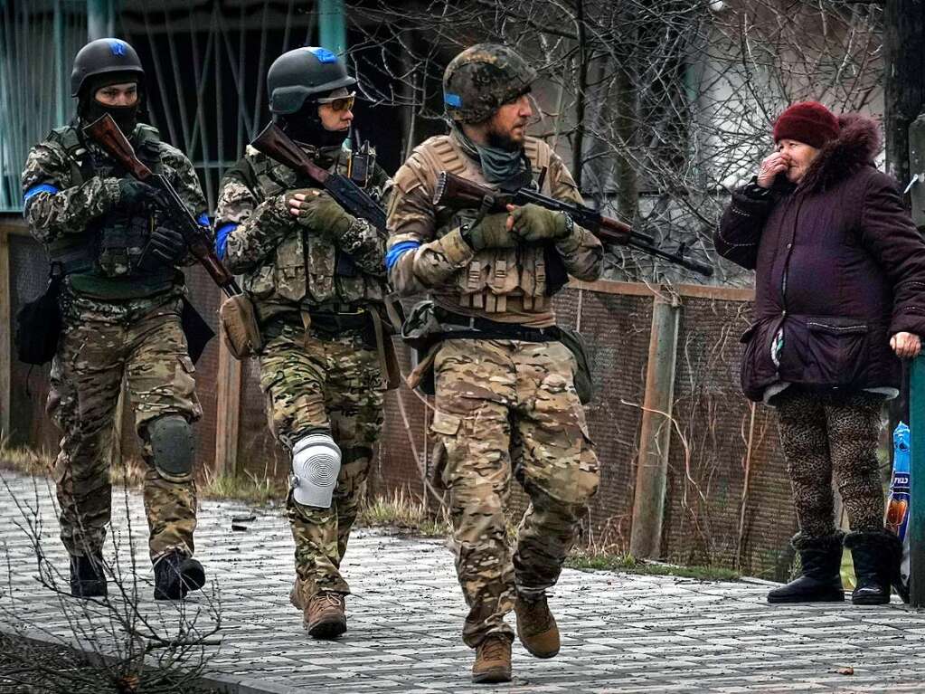 Eine Frau betrachtet ukrainische Soldaten, die in dem ehemals russisch besetzten Kiewer Vorort Butscha auf Patrouille sind.