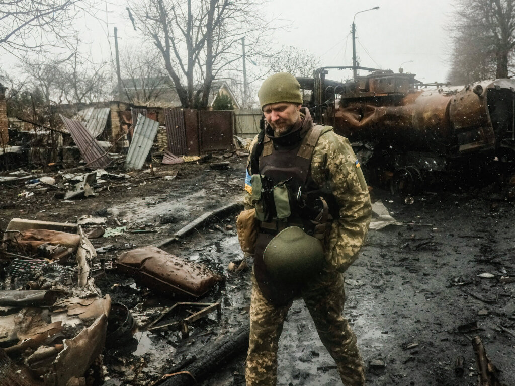 Ukrainische Soldaten inspizieren die Trmmer einer zerstrten russischen Panzerkolonne auf einer Strae in Butscha.