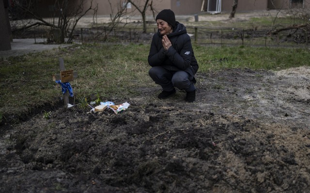Butscha: Die 57-jhrige Tanya Nedashki... der Stelle, an der er begraben wurde.  | Foto: Rodrigo Abd (dpa)