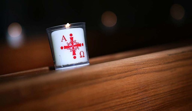 Eine brennende Kerze mit dem Aufdruck Alpha und Omega (fr Anfang und Ende)  | Foto: Ronny Hartmann (dpa)