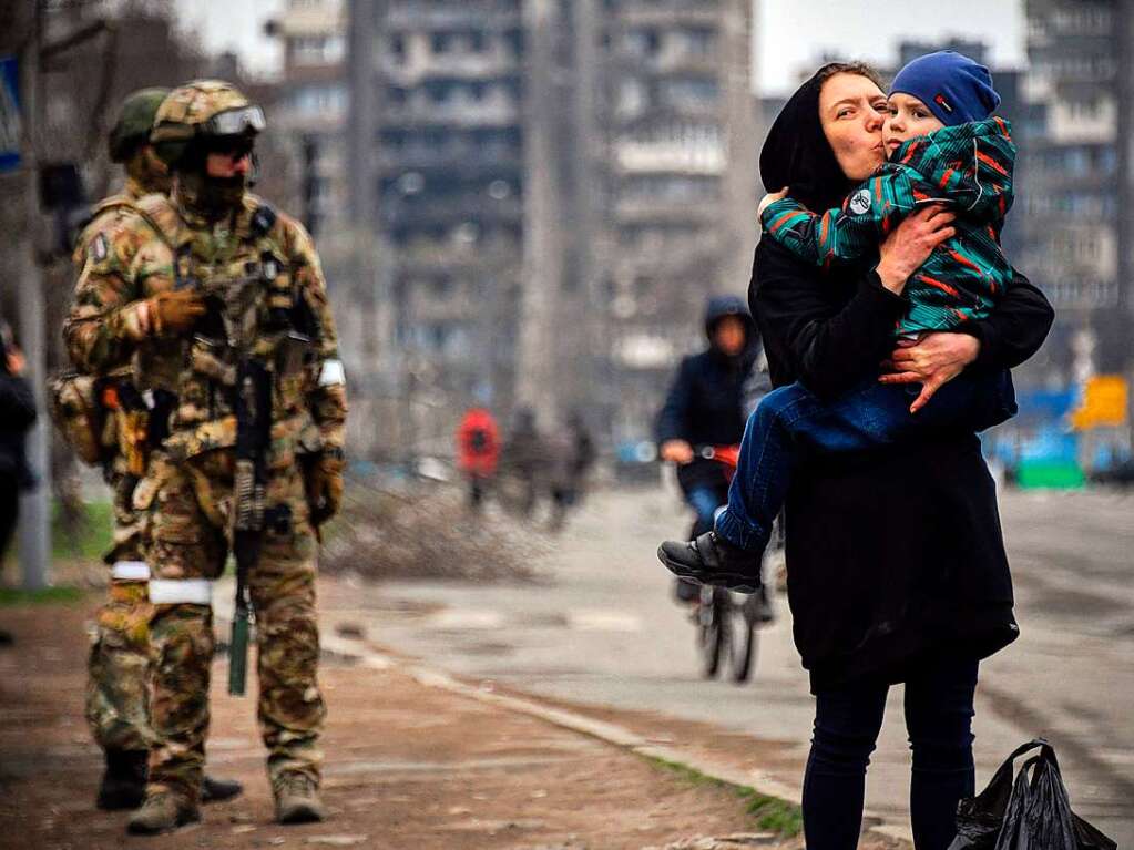 Eine Frau umarmt ein Kind in einer Strae von Mariupol, die unter russischer Kontrolle ist.