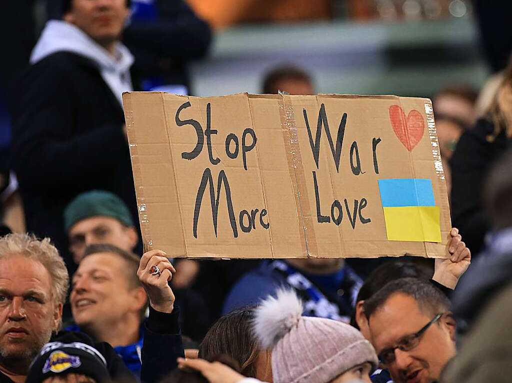 Fans halten auf der Tribne ein Plakat mit der Aufschrift "stop war more love".