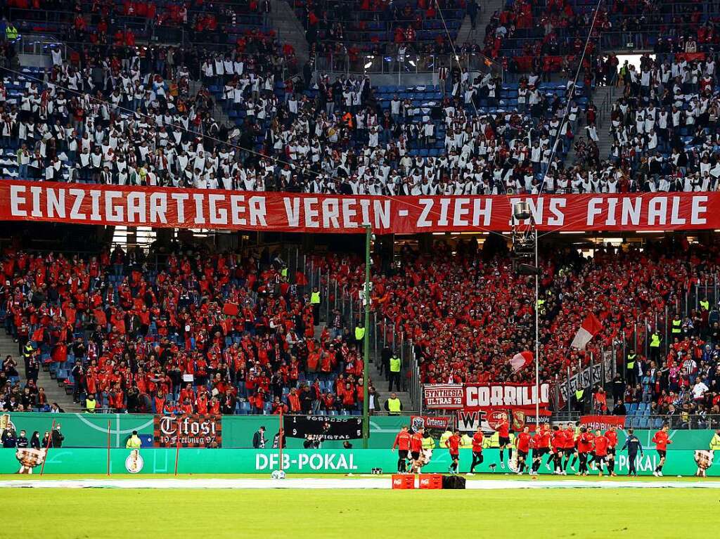 Die Spieler des SC Freiburg laufen sich vor dem Freiburger Fanblock warm.