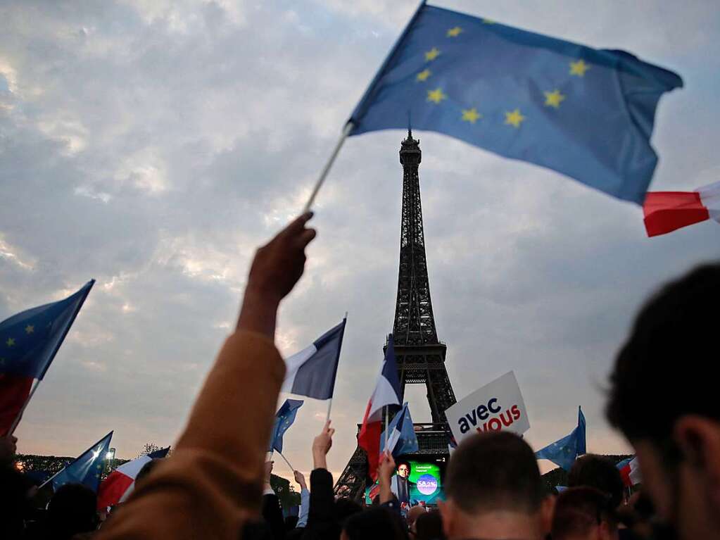 Anhnger des franzsischen Prsidenten Emmanuel Macron feiern am Eiffelturm mit Landesflaggen und Europafahnen.