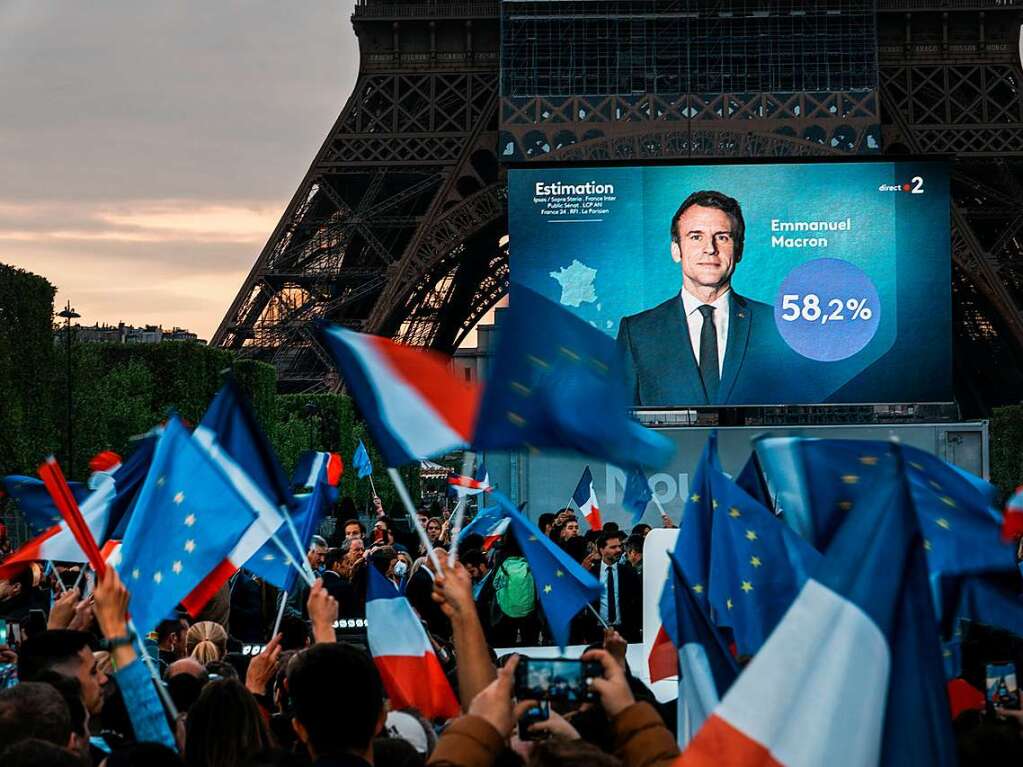 Emmanuel Macron, Prsident von Frankreich, auf einem Bildschirm vor dem Eiffelturm, als die ersten Wahlprognosen bekannt gegeben werden