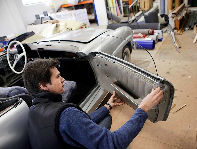 Ralf Herrenknecht arbeitet an der Lederverkleidung eines alten Mercedes.  | Foto: Christoph Breithaupt