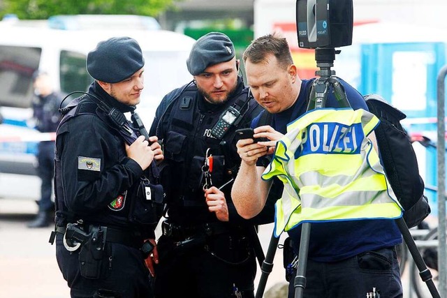 Polizisten untersuchen den Tatort am Marktplatz mit einer Kamera.  | Foto: Roland Weihrauch (dpa)