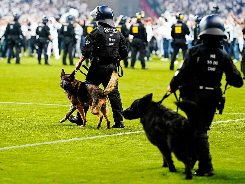 Polizisten beobachten die Fans von Eintracht Frankfurt auf dem Spielfeld nach der Partie.