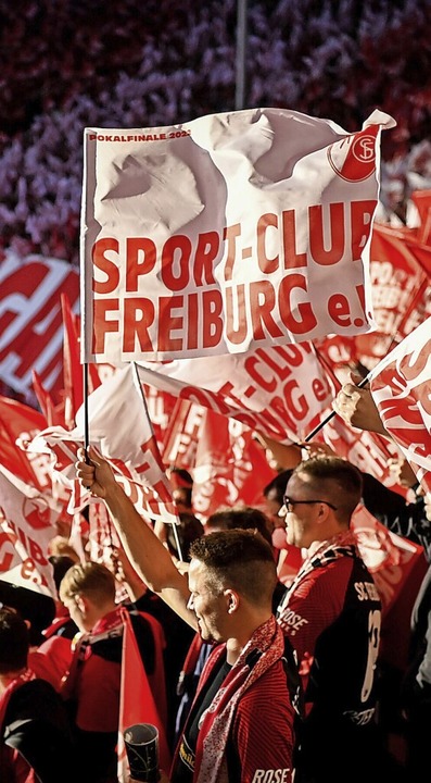 Im Berliner Abendlicht schwingen Anhänger des Sportclubs ihre Fahnen.  | Foto: Soeren Stache (dpa)