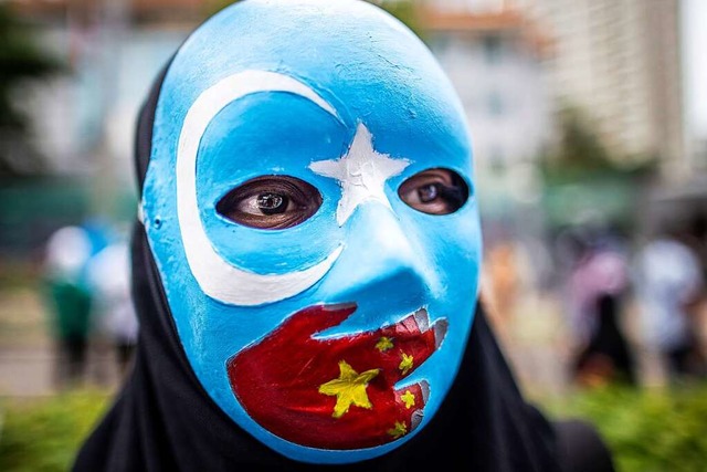 Diese Maske zeigt die Unabhngigkeitsf...r die Verfolgung der Uiguren in China.  | Foto: Donal Husni (dpa)