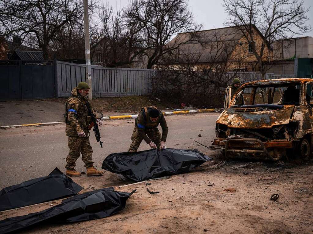 5. April: Zwei ukrainische Soldaten bergen die berreste von vier getteten Zivilisten aus einem verkohlten Fahrzeug in Butscha. Die Grueltaten an Bewohnern der Stadt sind nach Angaben von Prsident Selenskyj kein Einzelfall.