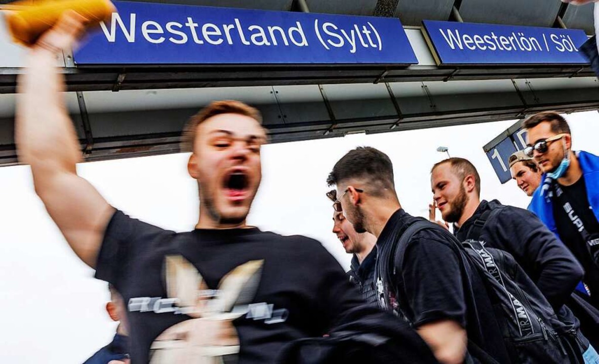 Ein Touristengruppe feiert auf dem Bahnhof von Westerland auf Sylt die Ankunft.  | Foto: Axel Heimken (dpa)