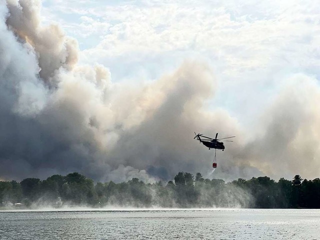 Ein Lschhubschrauber holt Wasser aus dem Seddiner See.  | Foto: Stephanie Pilick (dpa)