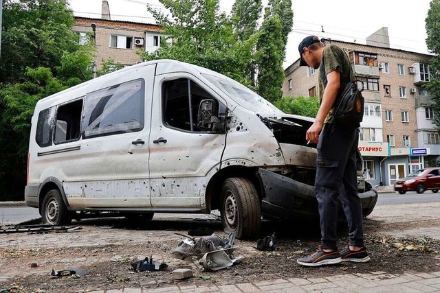 Ein Mann inspiziert ein Auto, das whr...im Osten der Ukraine beschdigt wurde.  | Foto: Alexei Alexandrov (dpa)