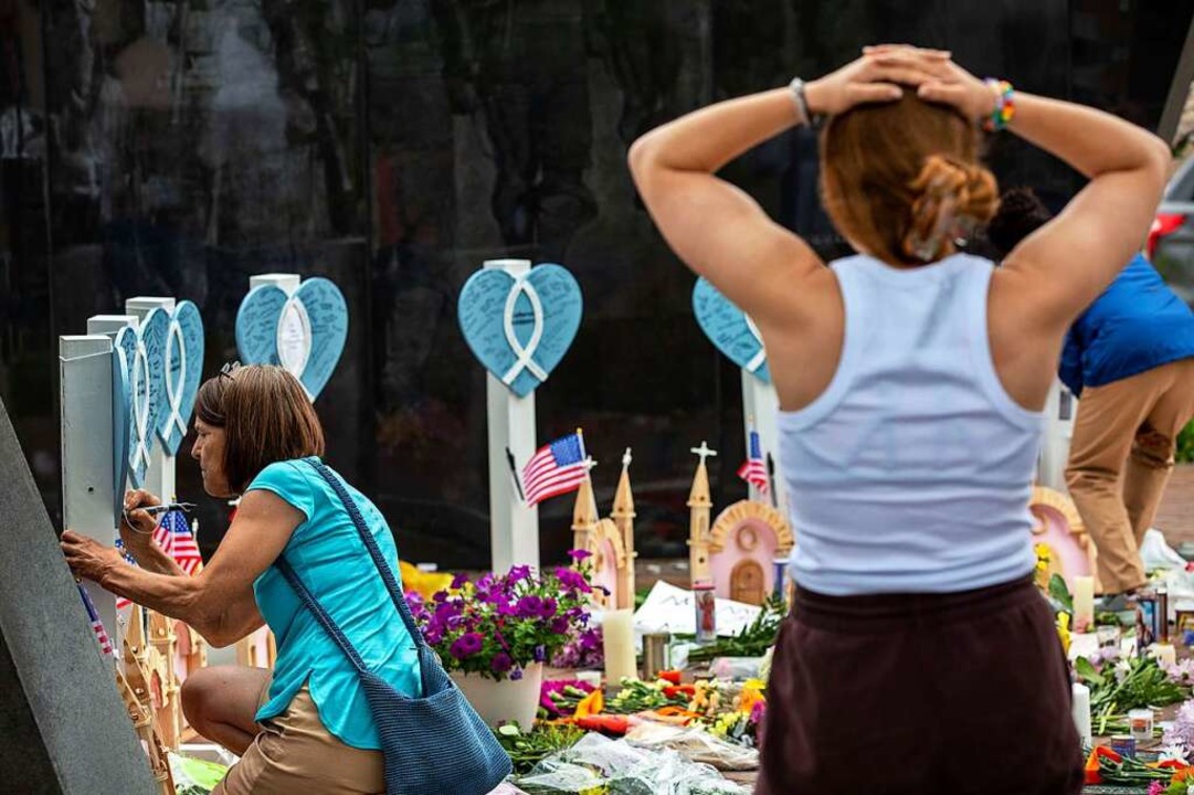 Menschen legen an einer improvisierten Gedenkstätte für die Opfer Blumen nieder.  | Foto: Jim Vondruska (AFP)
