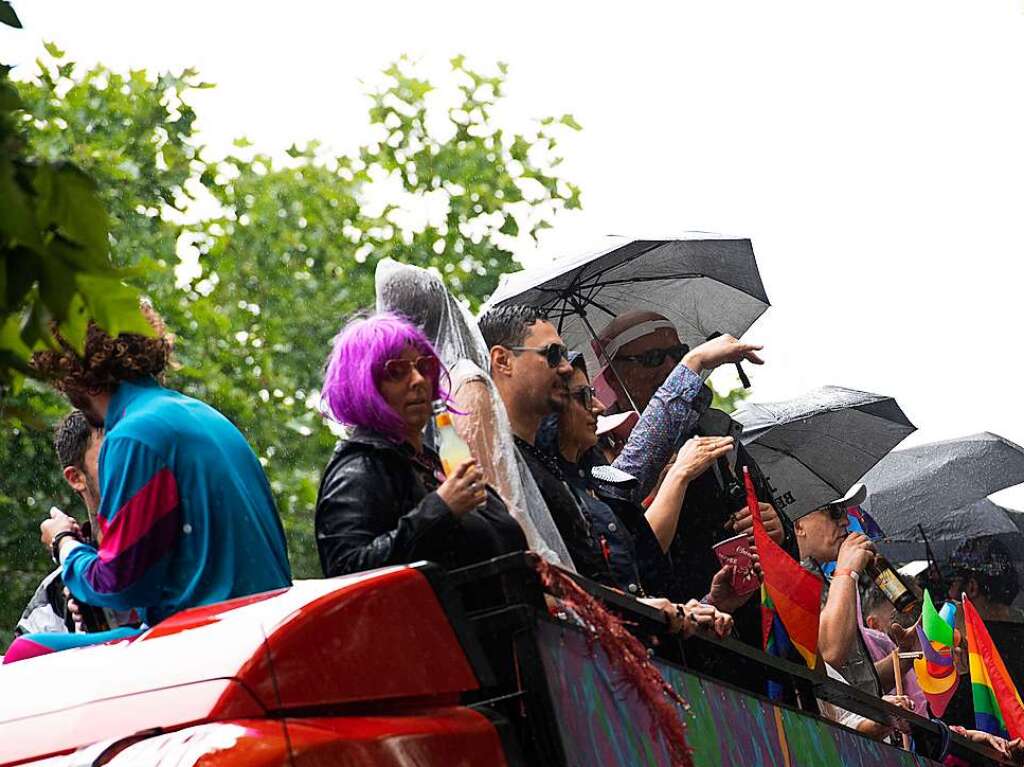 Gute Laune unter Regenschirmen zeigen diese Teilnehmer an der Rave the Planet-Parade auf einem Truck.