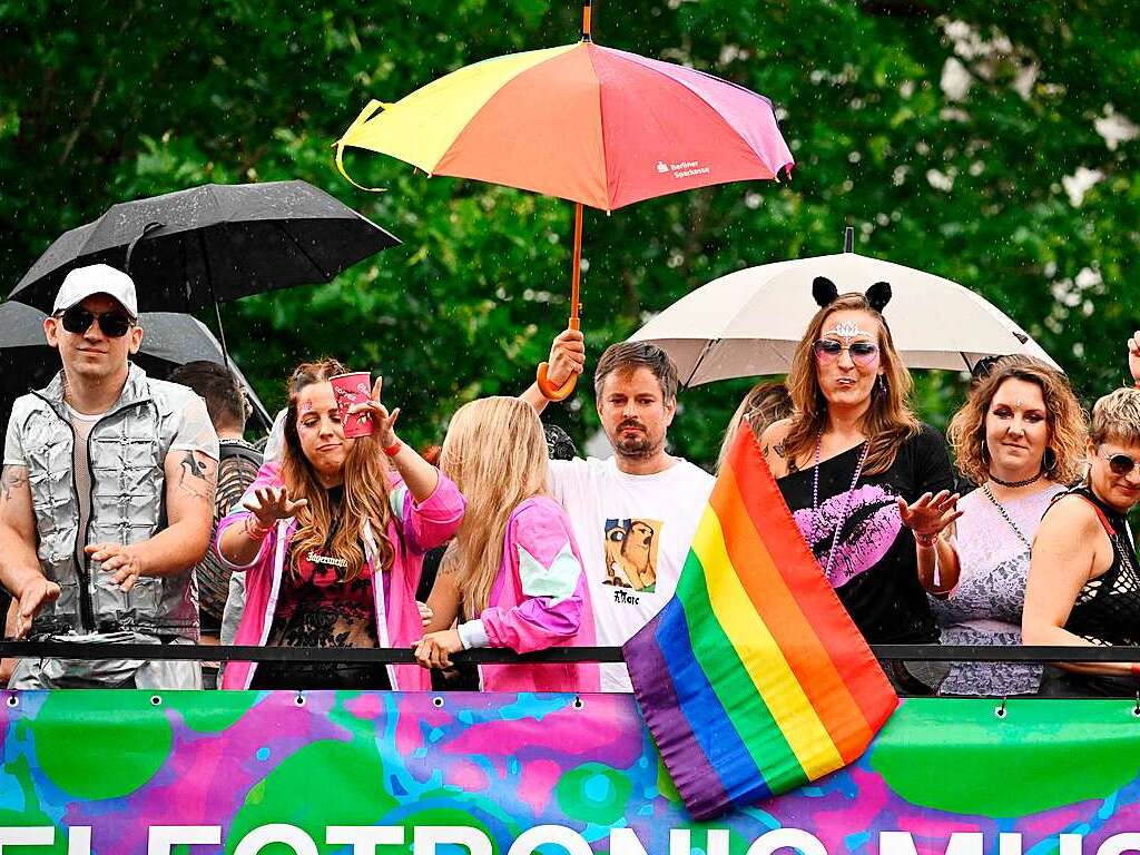 Gute Laune unter Regenschirmen zeigen diese Teilnehmer an der Rave the Planet-Parade auf einem Truck.