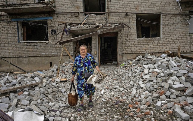 Eine Frau verlsst ihr Haus in Tschass...ne Rakete den Wohnblock getroffen hat.  | Foto: Nariman El-Mofty (dpa)