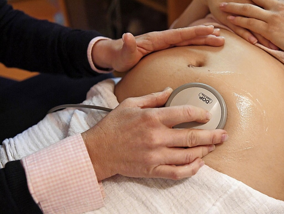 Eine Hebamme hört die Herztöne eines Babys im Mutterleib ab.  | Foto: Uli Deck (dpa)