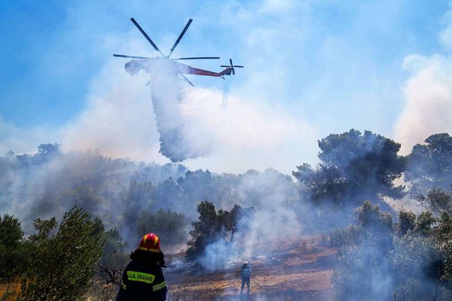 Ein Lschhubschrauber wirft im Osten A...ab, um einen Flchenbrand einzudmmen.  | Foto: Thanassis Stavrakis (dpa)