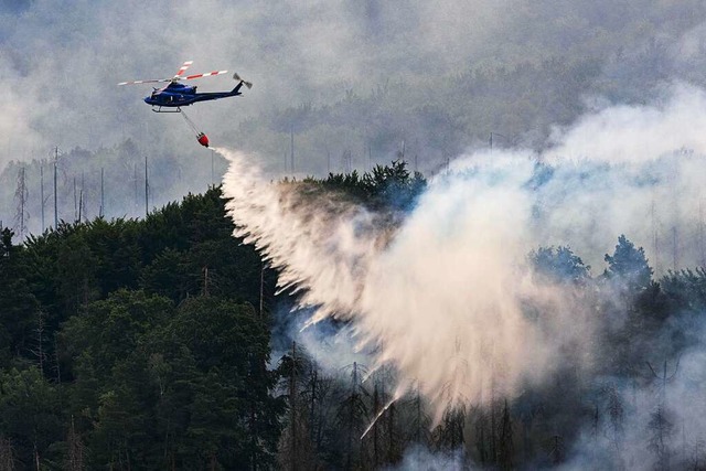 Mit einem Hubschrauber wird ein Waldbr...o nahe der Grenze zu Sachsen gelscht.  | Foto: Robert Michael (dpa)