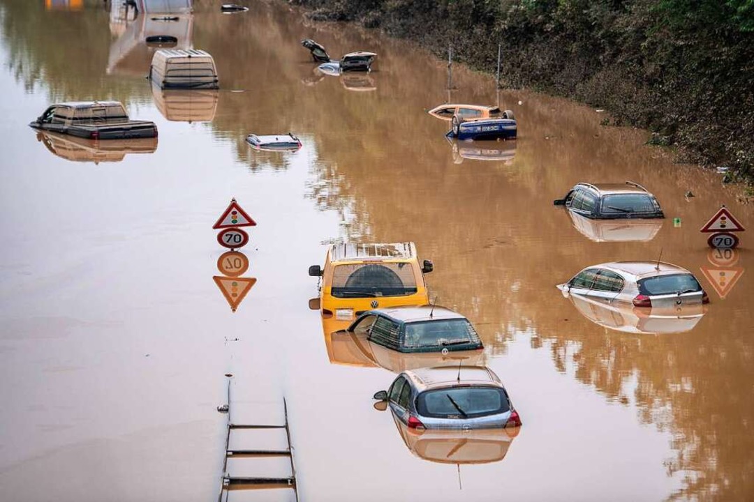 Autos stehen auf einer überfluteten Bundesstraße bei Erftstadt im Wasser.  | Foto: Marius Becker (dpa)