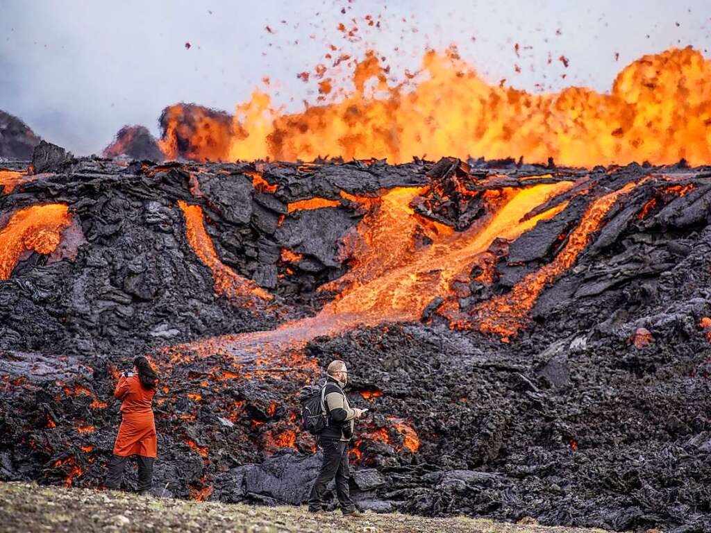 Menschen betrachten Lava, die auf dem Vulkan Fagradalsfjall fliet.