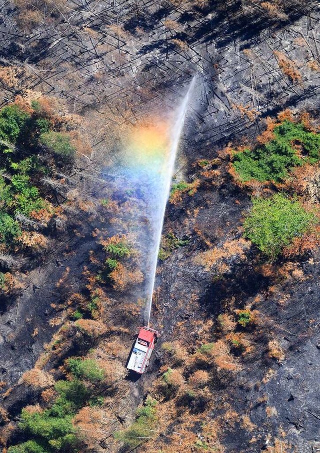 Im Strahl des Lschwassers einer Feuer...ark Schsische Schweiz ein Regenbogen.  | Foto: Robert Michael (dpa)