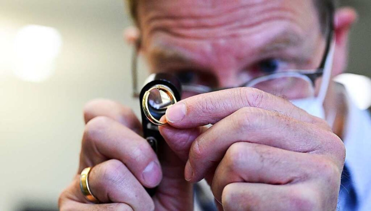 Ein Mitarbeiter der Städitischen Pfand...art taxiert einen Ring mit einer Lupe.  | Foto: Bernd Weißbrod (dpa)