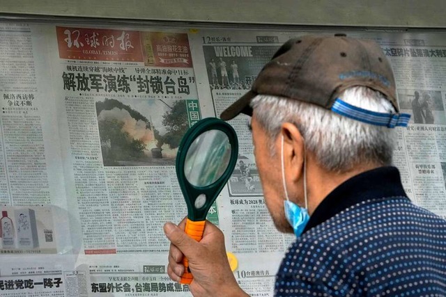 Zeitungen in Peking berichten aus chin...er mit einer  Lupe eine Zeitung liest.  | Foto: Andy Wong (dpa)